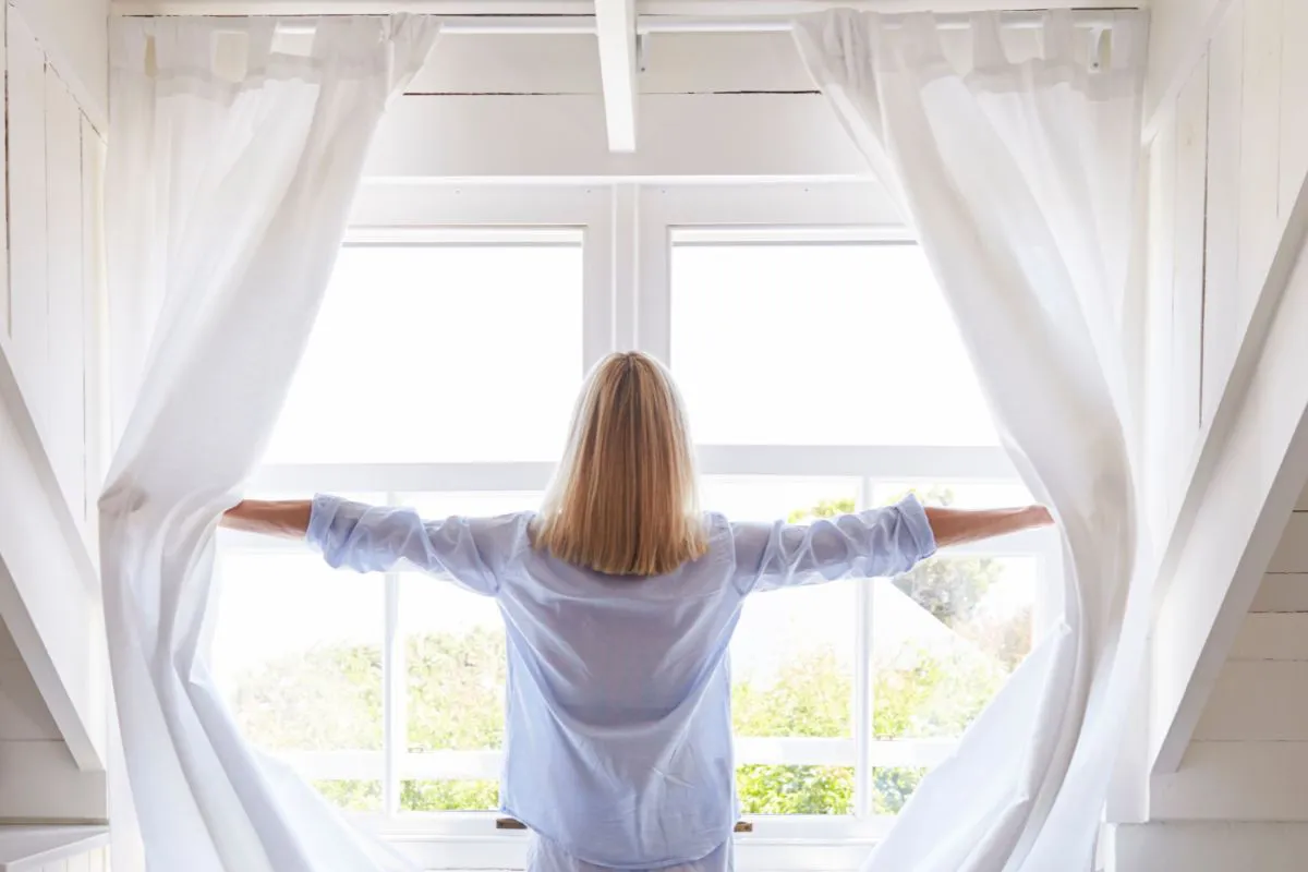 Een vrouw die de ramen open doet